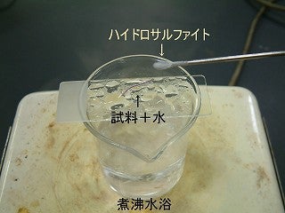 スライドガラスに脱色剤を滴下し、熱している様子の写真